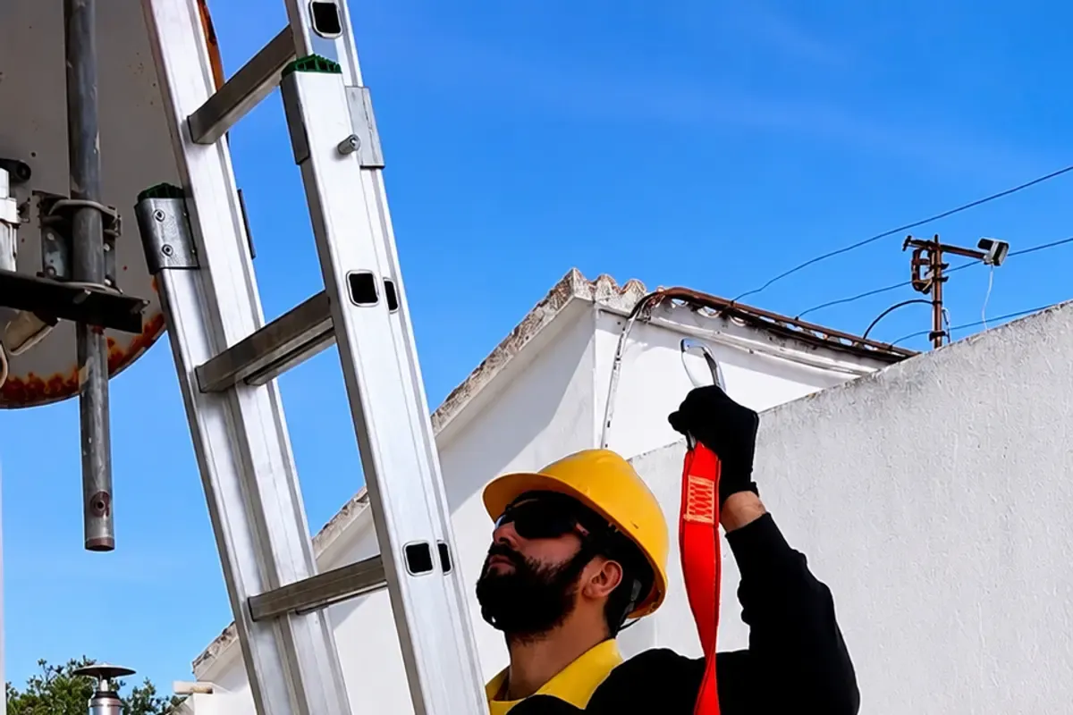 Instalador de Solartec trabajando con arnés y escalera de seguridad